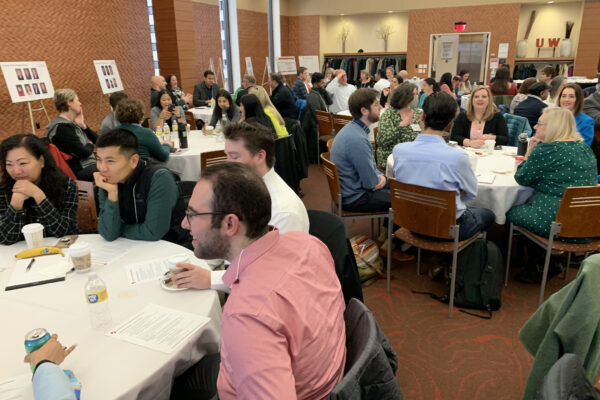 Photograph of a group of people engaging in conversation around tables