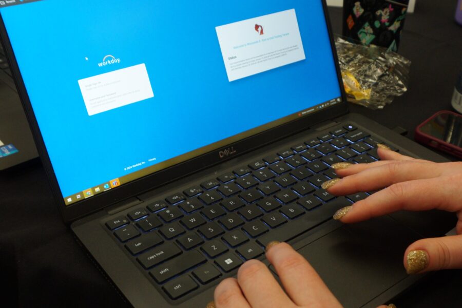 Photograph of the Workday login screen with hands typing on a laptop keyboard.
