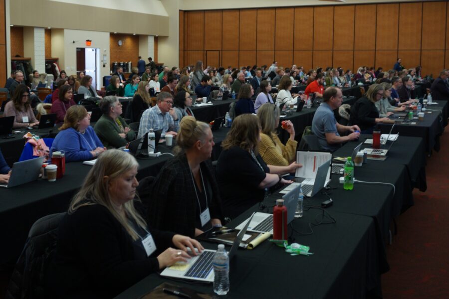 Photograph of large room filled with UW staff typing on computers, reviewing user manuals, or directing their attention to a speaker as part of ATP's UXT Preview event.
